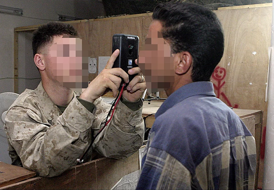 Figure 1: A US marine in Iraq takes a photograph of a man’s eyes. Source: “050610-M-0502E-010”, Marines, January 20, 2005.